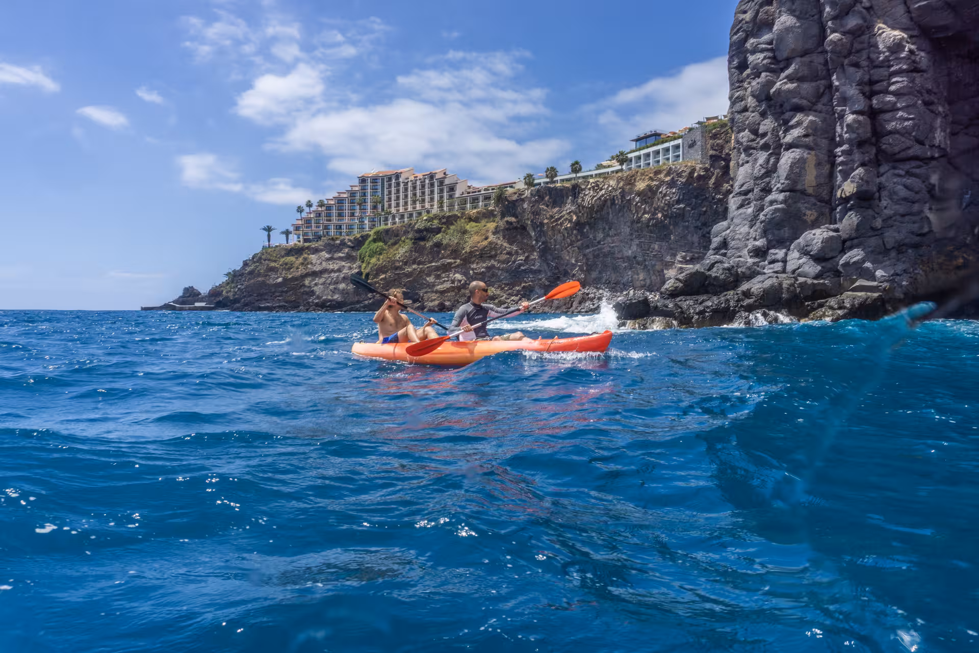 Kayakers exploring vibrant blue waters against a scenic rocky shoreline on a guided tour with snorkeling experiences.