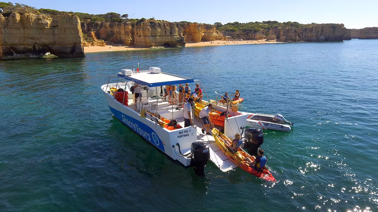 Support boat meets sea kayakers near Algarve golden cliffs and beach on guided Kayak and Coastline tour