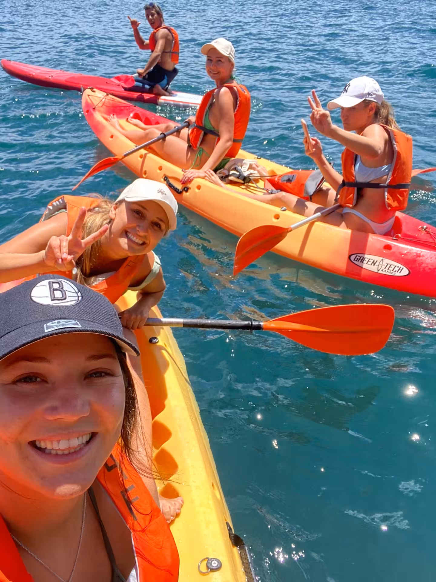 Group of friends enjoying a vibrant kayak adventure on the clear waters of Benagil, Algarve, in sunny weather.