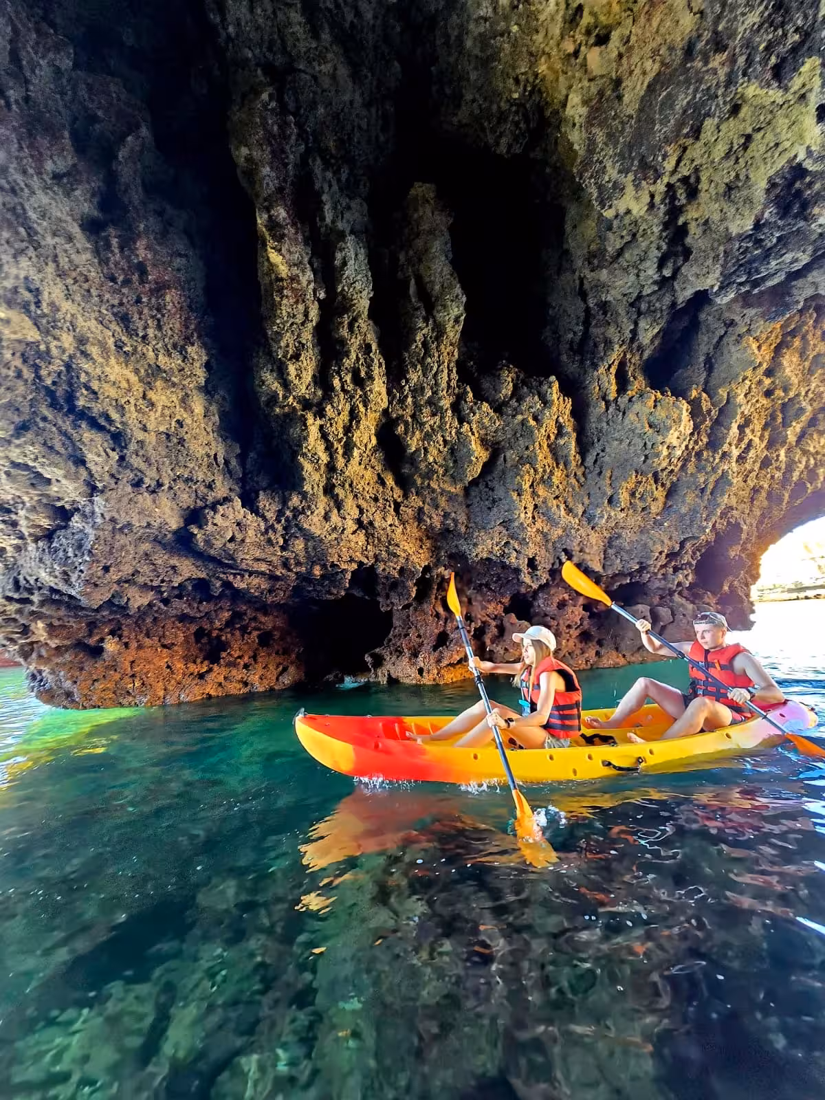 Two kayakers in life jackets paddling through stunning Albufeira sea caves on crystal clear turquoise waters