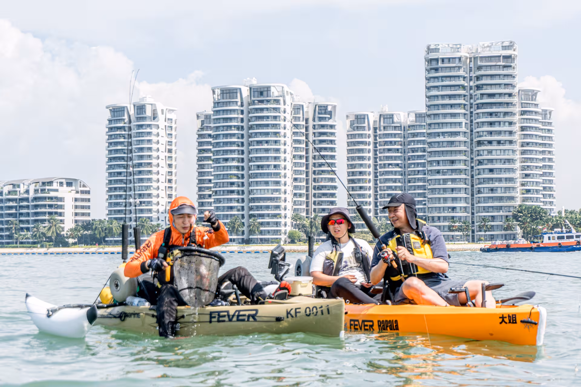 Three kayakers fishing near modern buildings on Saint John Island tour.