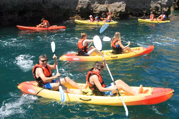 Kayakers in life jackets paddling near Ponta da Piedade sea caves, Lagos Algarve guided kayak tour on clear water