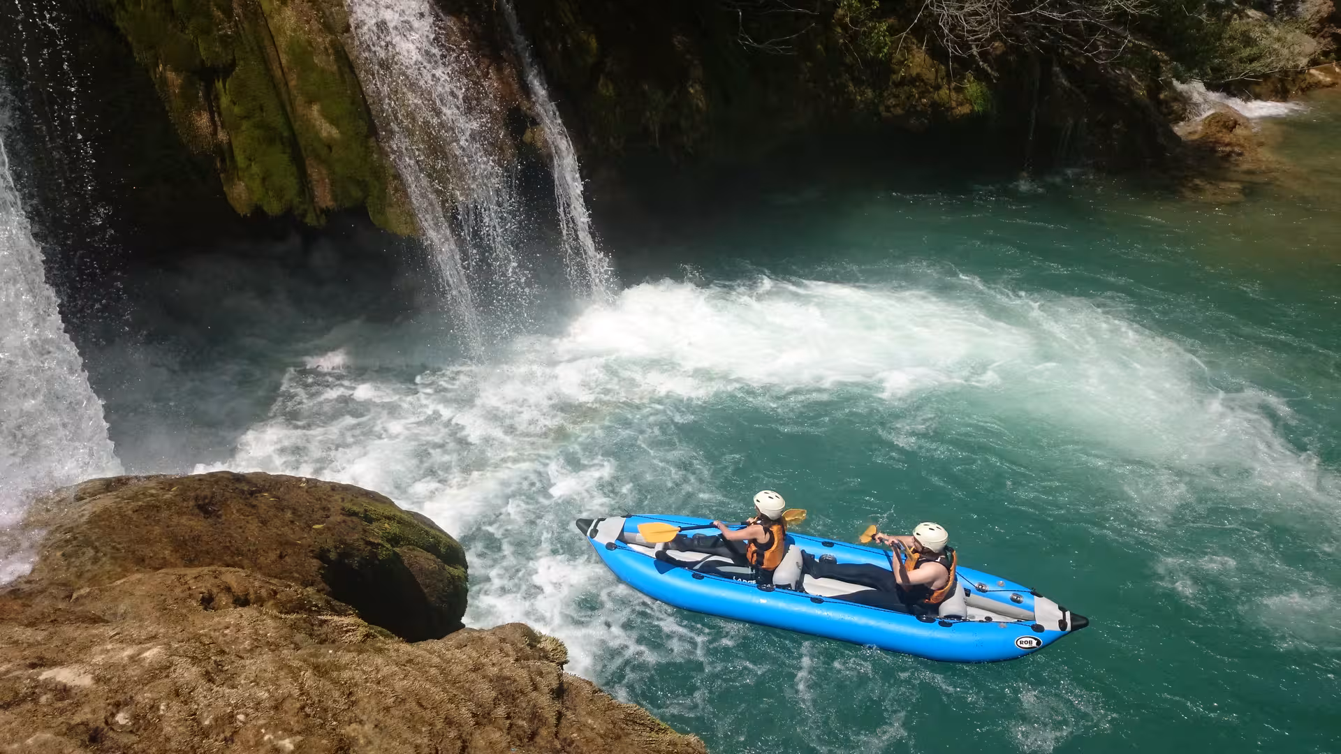 Adventurers kayaking through the stunning Mreznica Canyon waterfall, enjoying thrilling rapids and lush scenery.