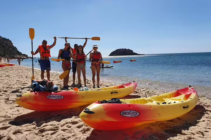 Group of kayakers in vibrant gear ready for a kayaking and snorkeling adventure on a sunny beach in Lisbon, Portugal.