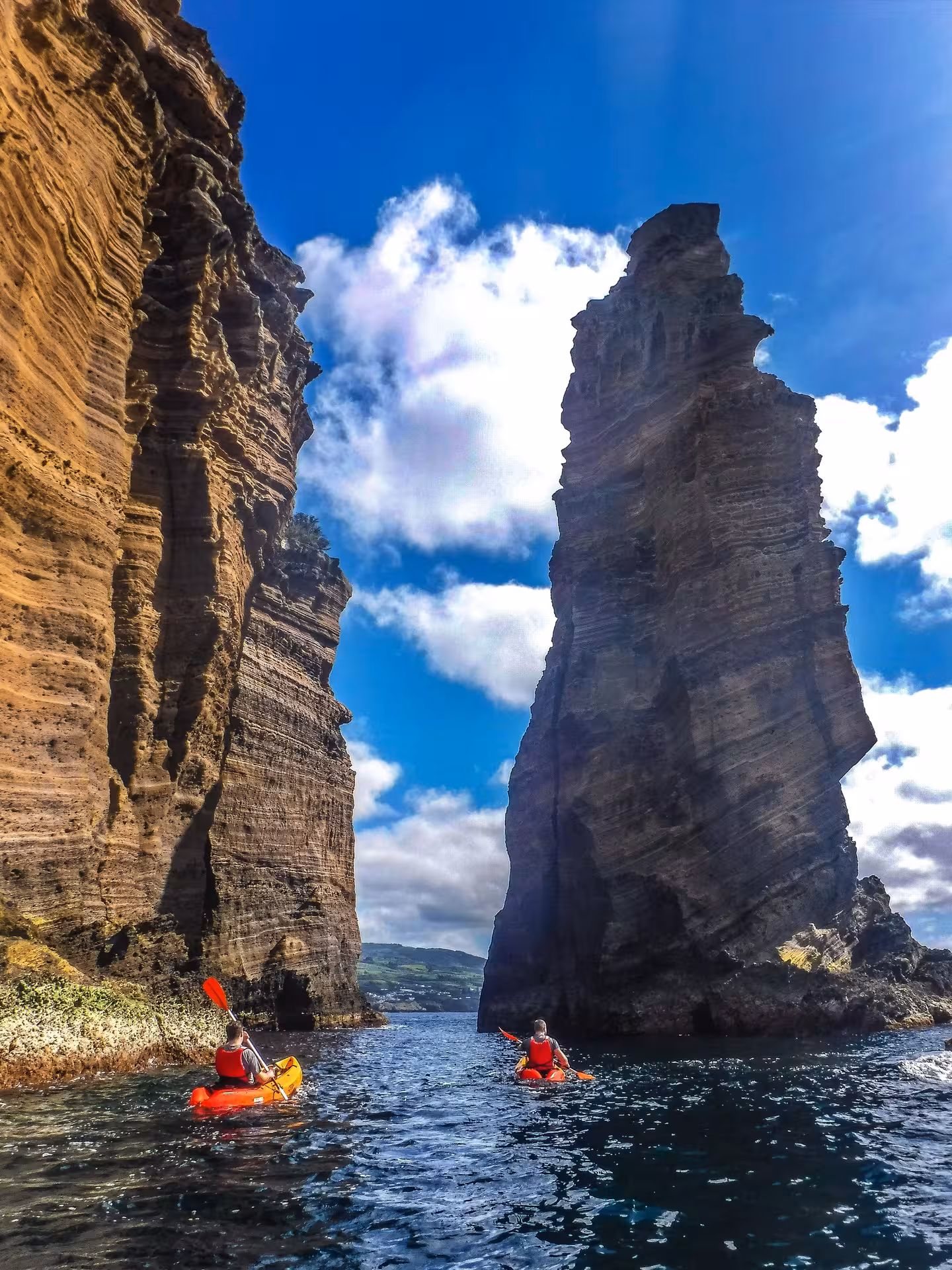 Kayakers exploring towering sea cliffs near Vila Franca do Campo, São Miguel Azores, guided ocean kayaking adventure