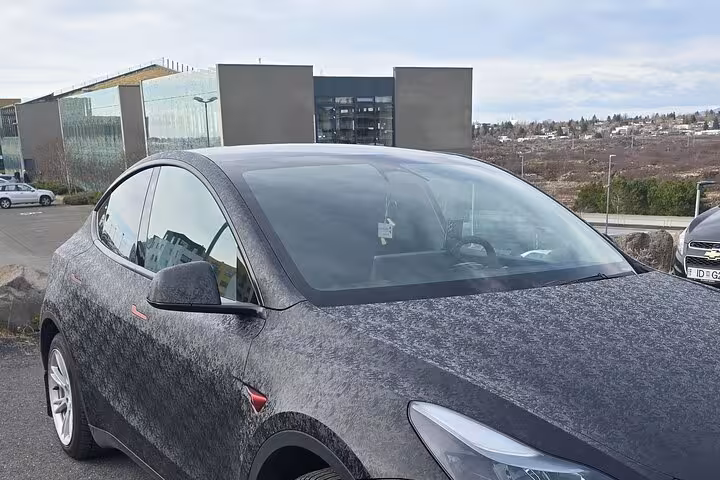 Sleek black car parked at Keflavik Airport, ideal for private transfer to Reykjavik.