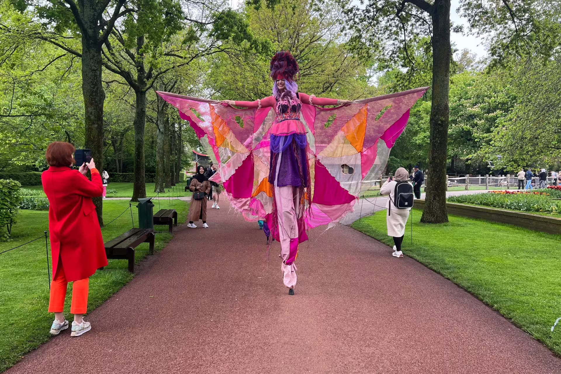 Colorful stilt performer at Keukenhof Gardens walkway, a highlight of the Amsterdam Keukenhof and Giethoorn tour