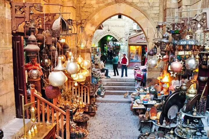 Khan El Khalili bazaar alley with hanging lanterns and brassware, Cairo shopping stop from Alexandria Port