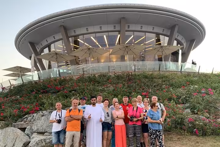 Tour group at Khorfakkan amphitheatre viewpoint, cultural stop on Fujairah mountains safari sightseeing tour