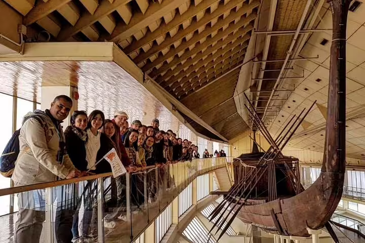 Tour group viewing the ancient Khufu solar boat at the Grand Egyptian Museum on a private Cairo day tour