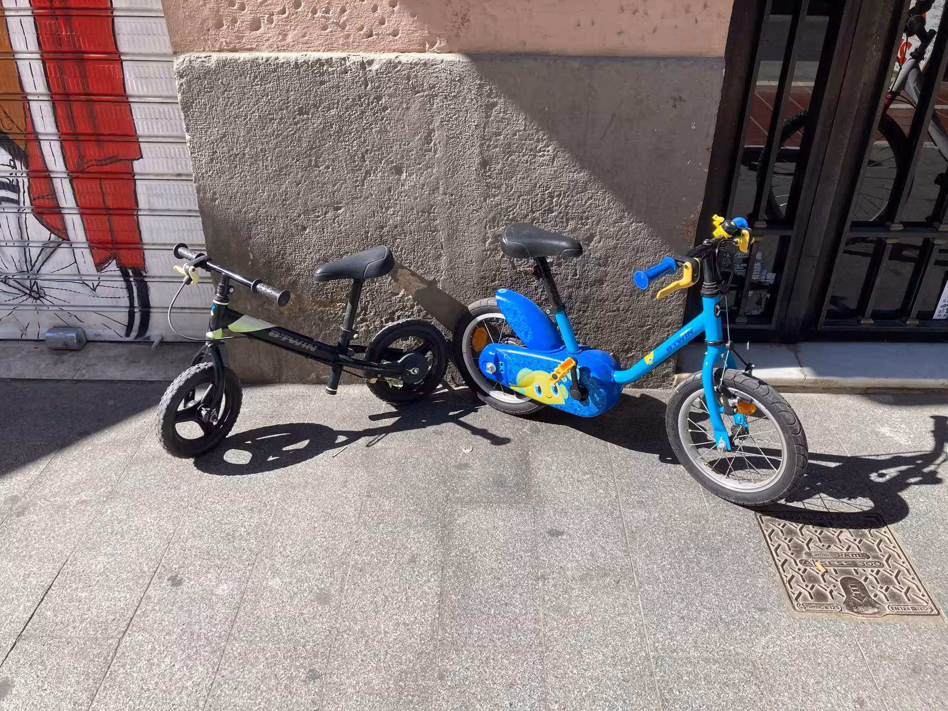 Kids city bike rental options with balance bike and small pedal bike on sidewalk, ideal for family rides