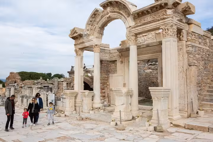 Family with kids exploring Ephesus ruins on a Kusadasi Port shore excursion, ancient Roman archway