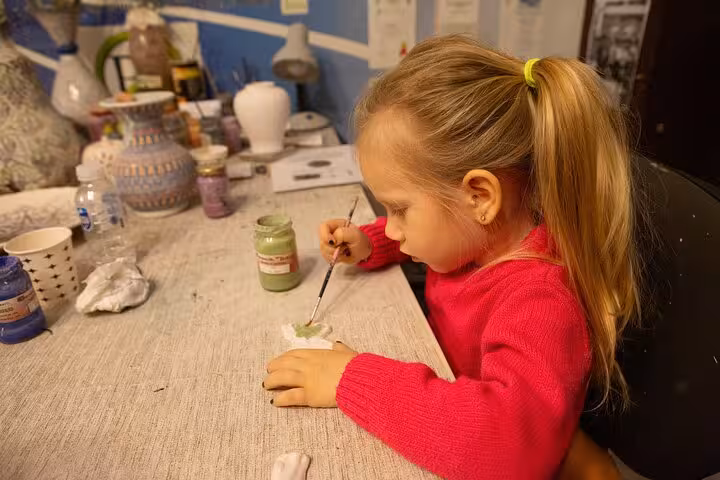 Child painting Turkish ceramic at a kid-friendly Ephesus shore excursion from Kusadasi Port craft stop