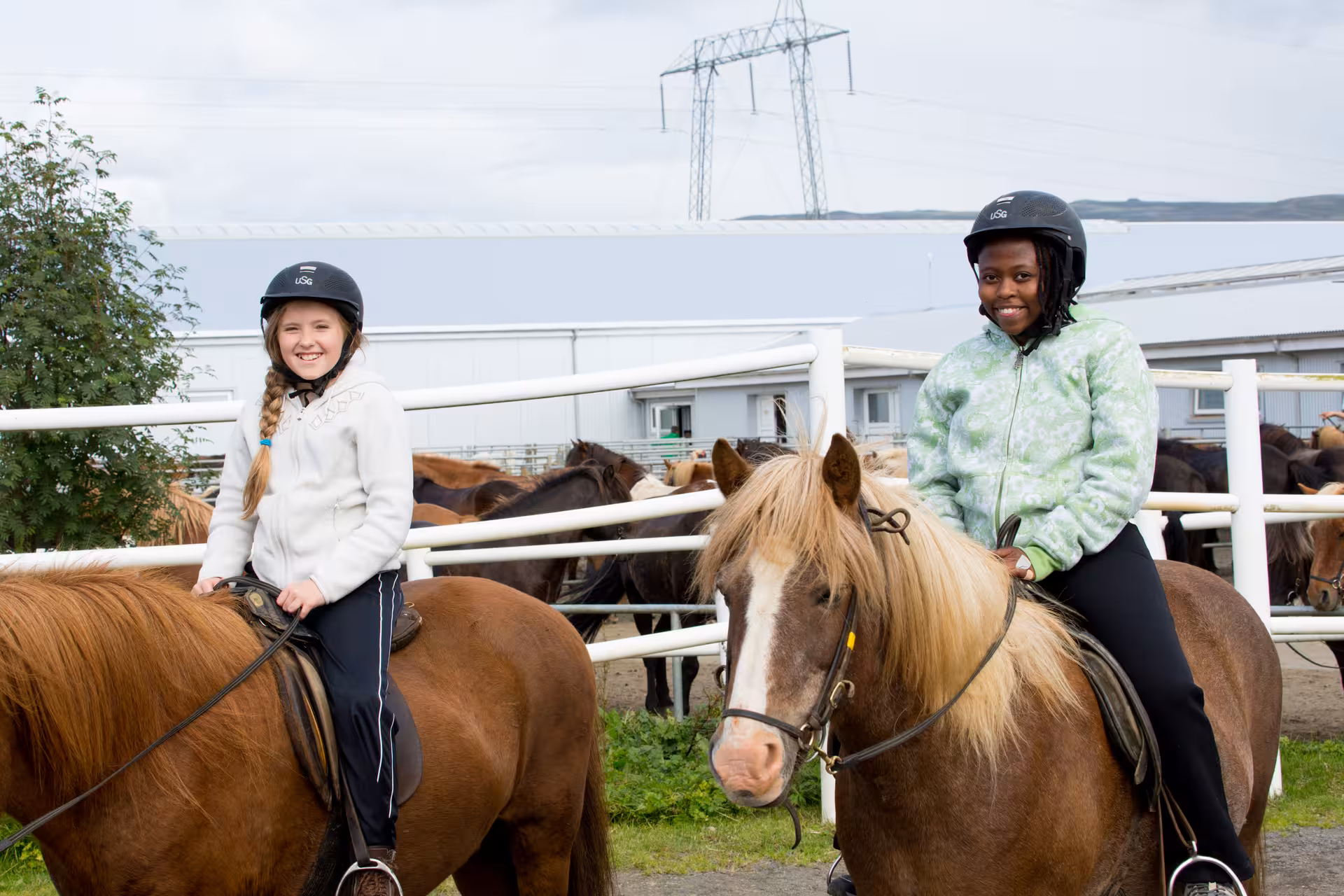 Smiling kids on Icelandic horses at a countryside stable, family-friendly riding on the Countryside Charm tour
