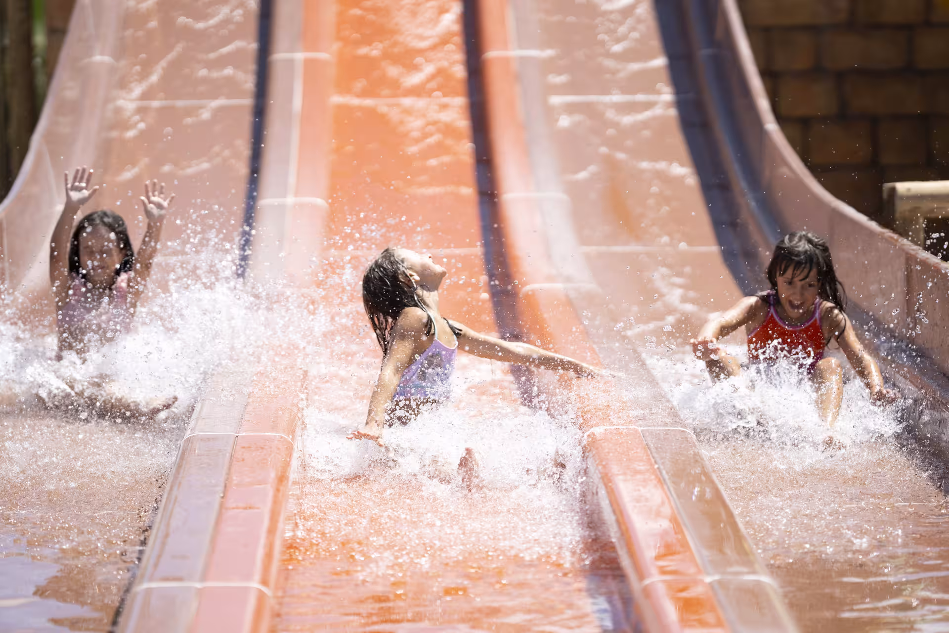 Kids splashing down multi-lane water slide at MagicSplash near Rome, perfect family waterpark day trip