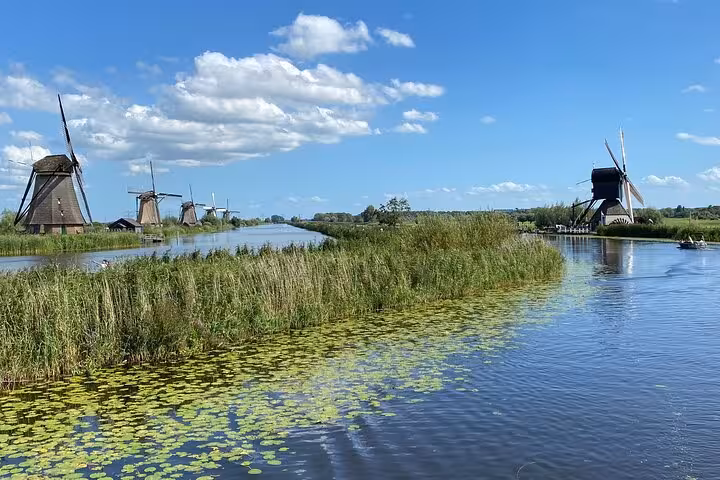 Kinderdijk windmills and canals under blue skies, highlight of Famous Holland day tour from Amsterdam