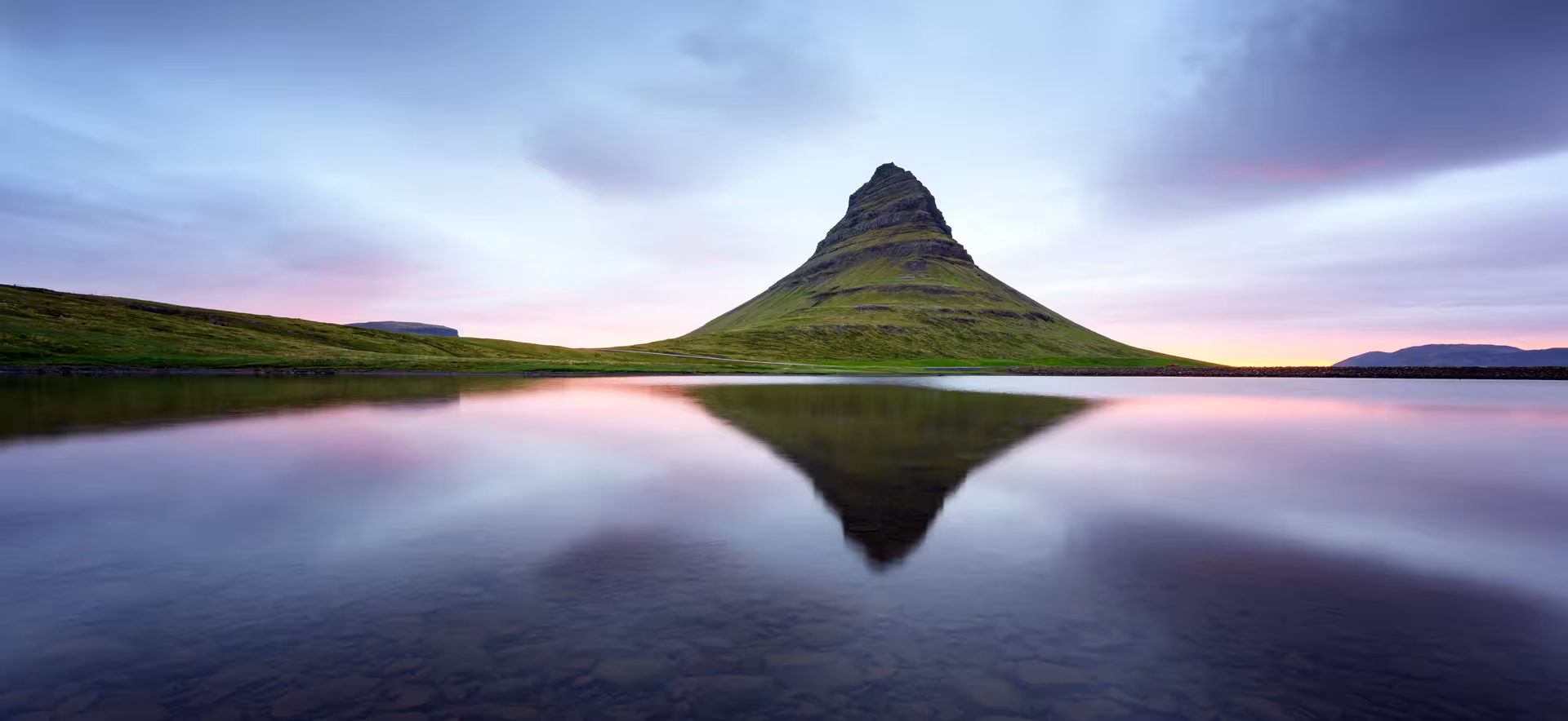 Kirkjufell mountain reflecting in calm waters during a serene sunset on Snæfellsnes Peninsula private day tour.