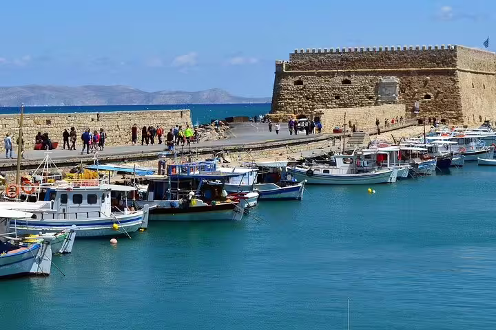 Historic Venetian fortress in Heraklion with colorful boats docked along the vibrant harbor, ideal for Knossos Palace tours.