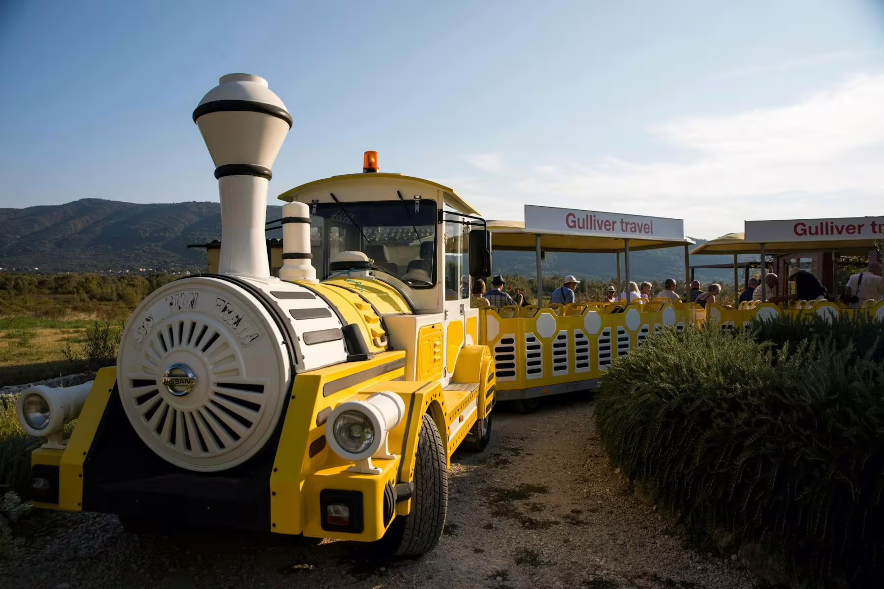 Yellow tourist train ride in Konavle Valley near Dubrovnik, passengers heading to winery for guided wine tasting