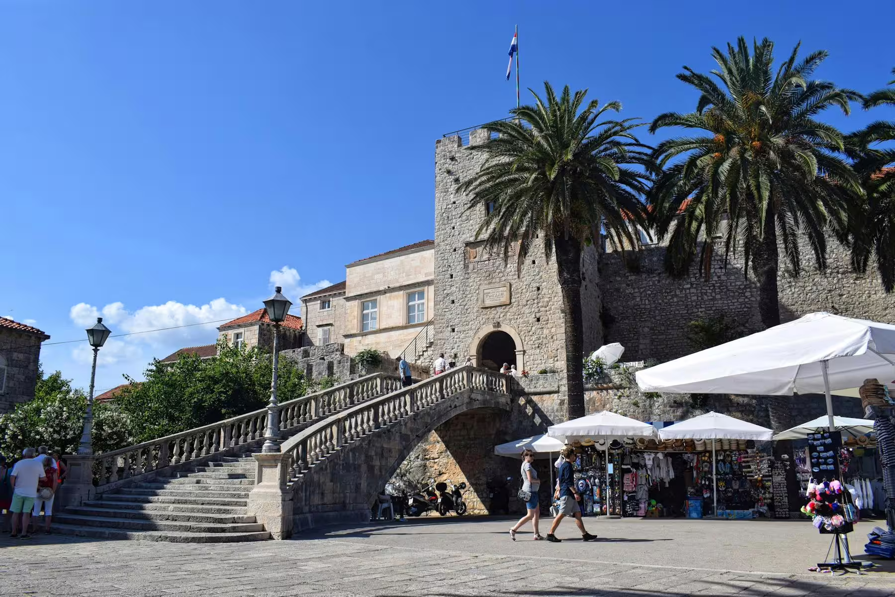 Korcula Old Town stone gate and palm-lined square, stop on Legends of Peljesac & Korcula tour from Dubrovnik