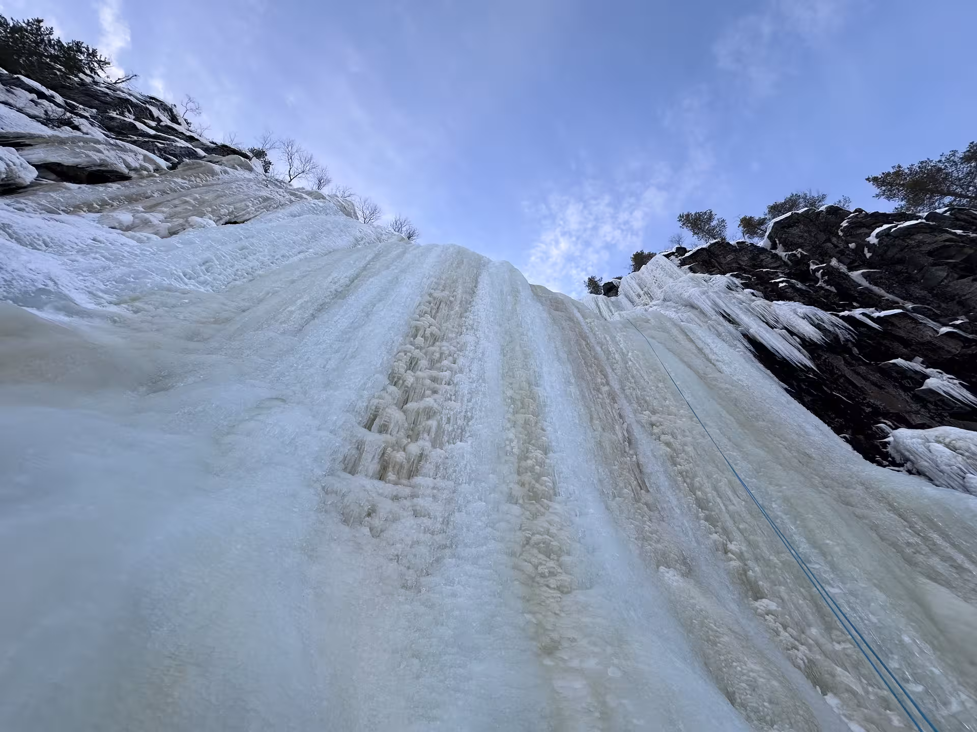 Dramatic upward view of Korouoma's towering frozen waterfall, ideal for ice climbing enthusiasts.