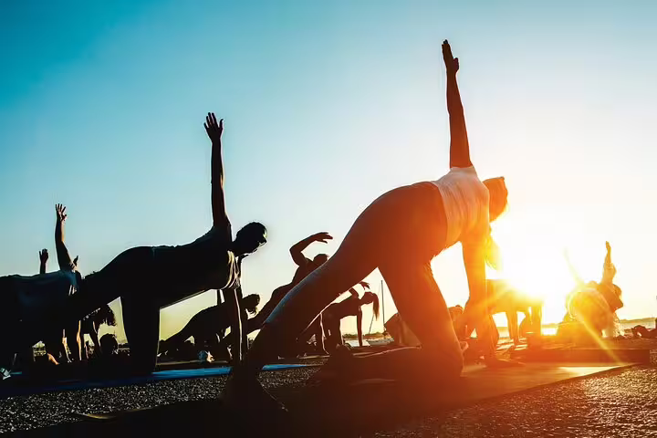 Group practicing yoga at sunrise on Kos island, silhouetted against a vibrant sky.