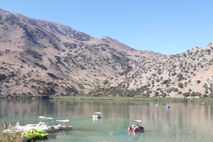 Scenic view of Kournas Lake with pedal boats against a backdrop of rugged mountains, part of the West Crete private tour.