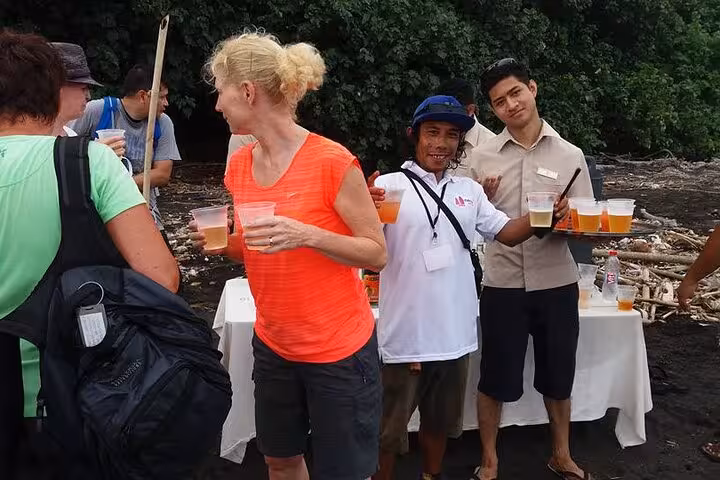 Tourists enjoy welcome drinks on Anak Krakatau black-sand beach during Krakatoa day tour from Jakarta
