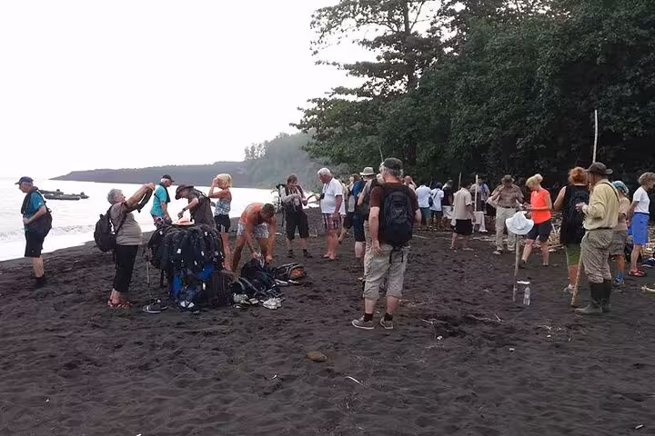 Group gathers on Krakatau black-sand shoreline before trekking Anak Krakatau volcano on a Krakatoa day tour