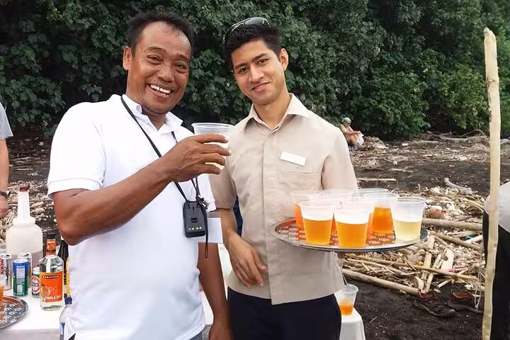 Local guides serve refreshments on Krakatau Island beach stop, a highlight of the Krakatoa day tour Indonesia