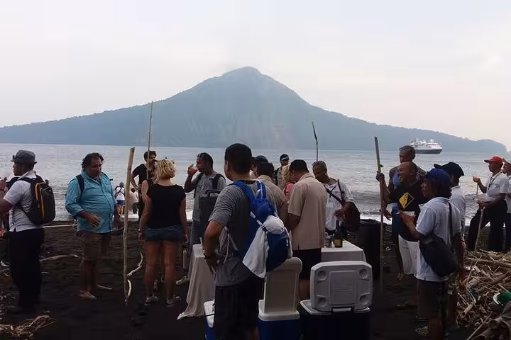 Travelers gather on black-sand beach with Krakatau volcano view during Krakatoa day tour from Jakarta