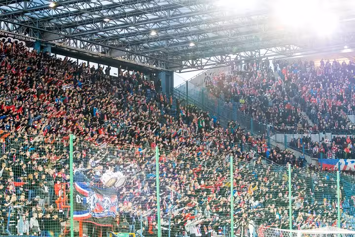 Join a Krakow football match with a local, huge home crowd in covered stand with flags and banners