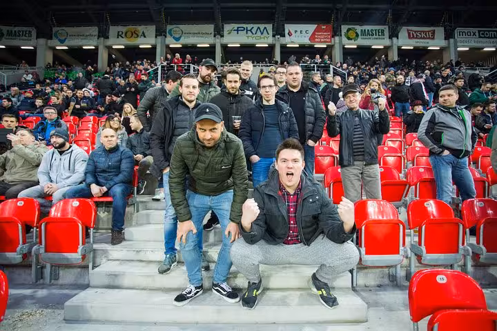 Excited supporters posing in red seats, Krakow soccer match experience with local host and authentic fan culture