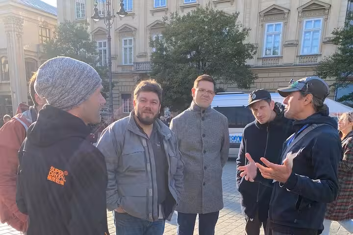 Tour guide engaging visitors during a walking tour in Krakow's Jewish Quarter, with historic buildings in the background.