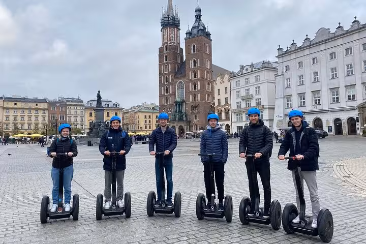 Group enjoying Krakow Segway tour in historic square with iconic church backdrop.