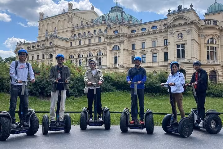 Segway riders in front of Krakow's grand architecture, enjoying a private tour under a clear sky.