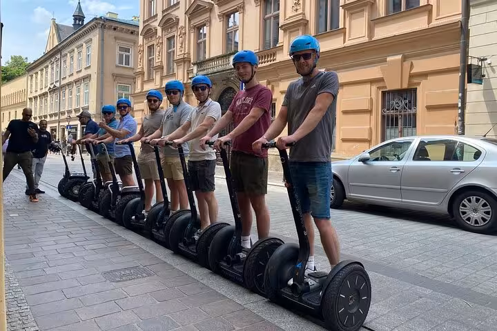 Tourists enjoying a sunny Krakow Segway tour, lined up in helmets, exploring the city's charming streets.