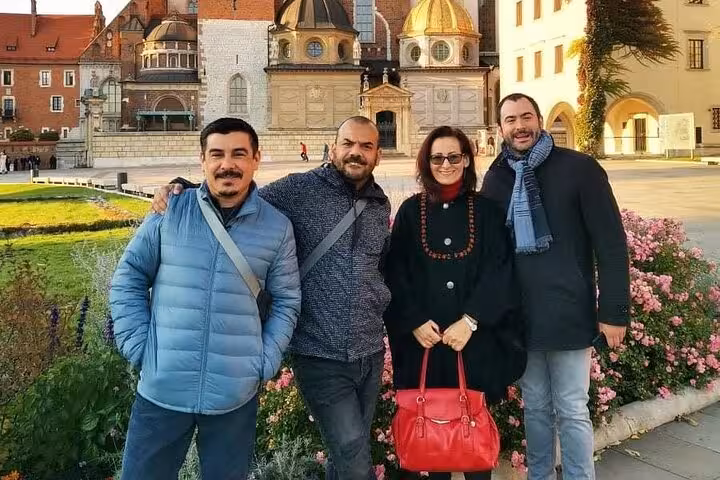 A group of tourists enjoying a sunny day at Krakow's historic Wawel Castle during a magical walking tour.