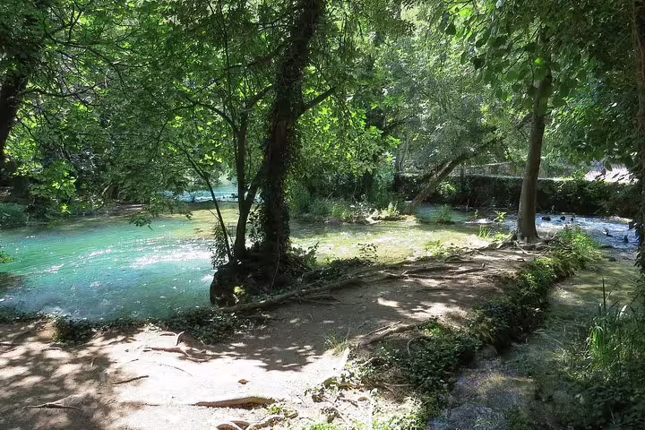 Shaded riverside trail beside turquoise Krka River in Krka National Park, Croatia, on waterfalls tour