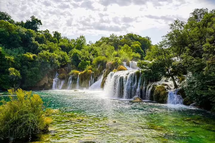 Panoramic Krka National Park waterfalls and clear green river, scenic stop on Krka and Trogir shore tour