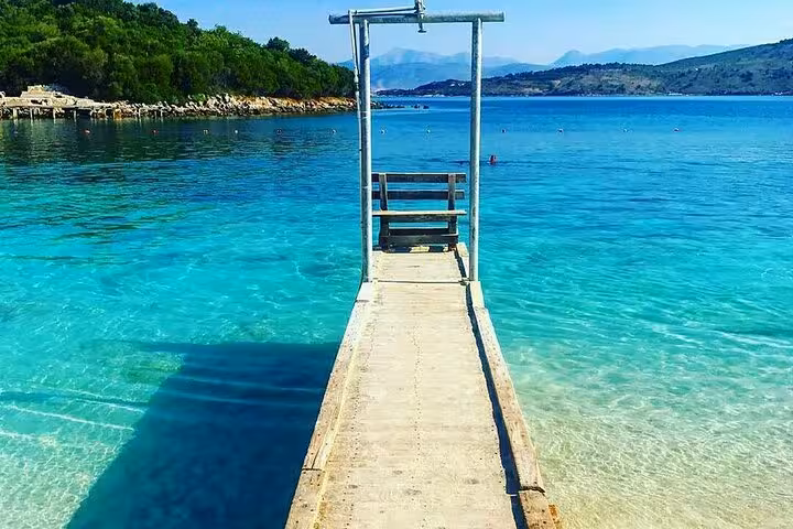Relax on the serene beaches of Ksamil, Albania, with crystal-clear turquoise waters and a picturesque wooden pier.