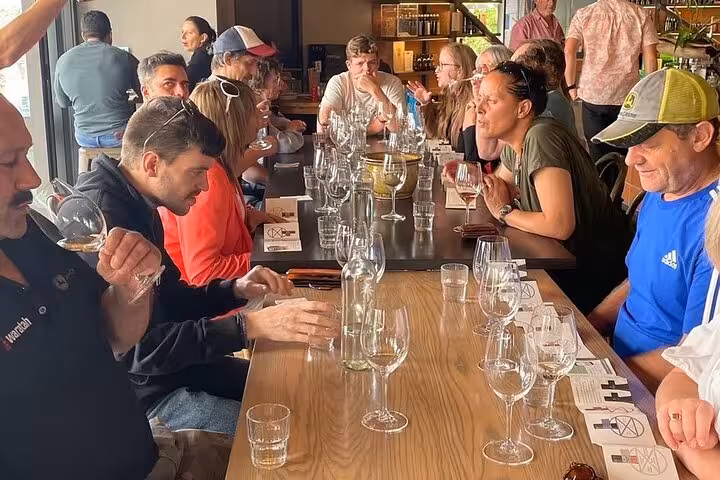 Visitors enjoying a wine tasting session at Kumeu, surrounded by glasses and lively conversation.