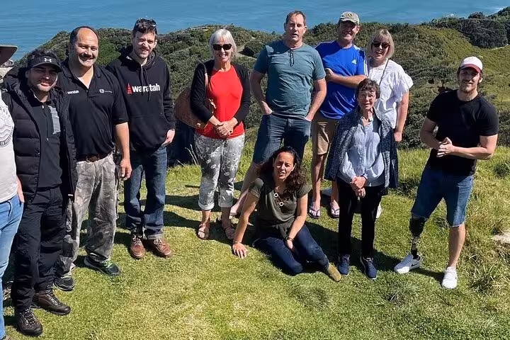 Group of tourists enjoying a sunny day with ocean views on the Kumeu Wine Tour.