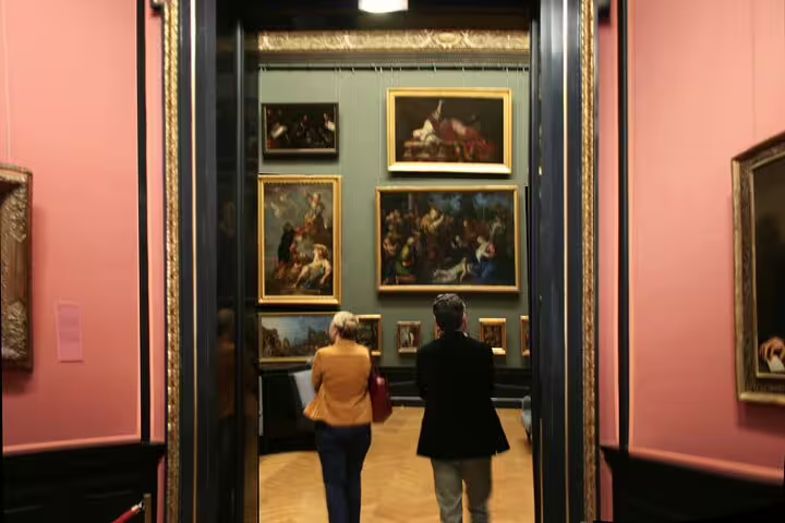 Visitors exploring a vibrant gallery of classic paintings at Vienna’s Kunsthistorisches Museum.