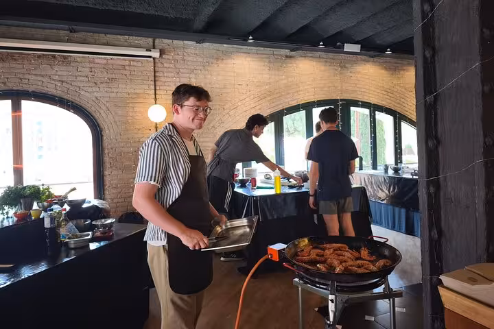 A guest prepares delicious seafood at the La Boqueria Market Tour & Premium Cooking Class in a chic loft.
