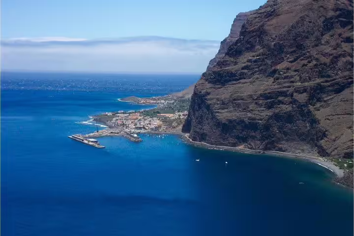 Breathtaking aerial view of La Gomera's rugged cliffs and serene harbor, perfect for the island tour from Tenerife.