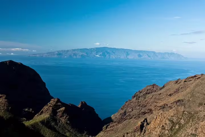 Scenic view of La Gomera from Tenerife with expansive ocean and rugged cliffs under a clear blue sky.