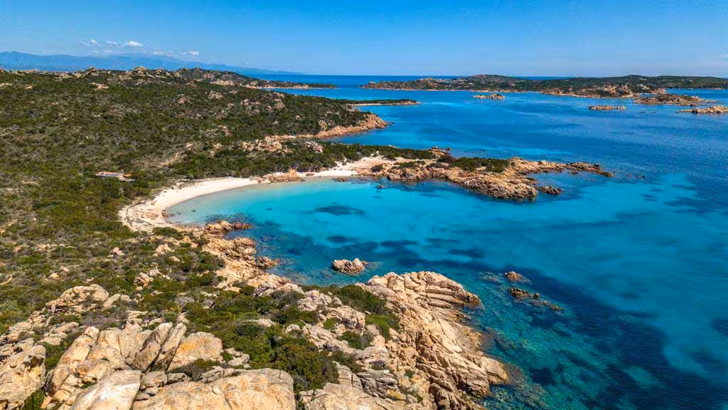 Aerial view of a pristine beach with turquoise waters in the La Maddalena Archipelago, ideal for a dinghy tour.