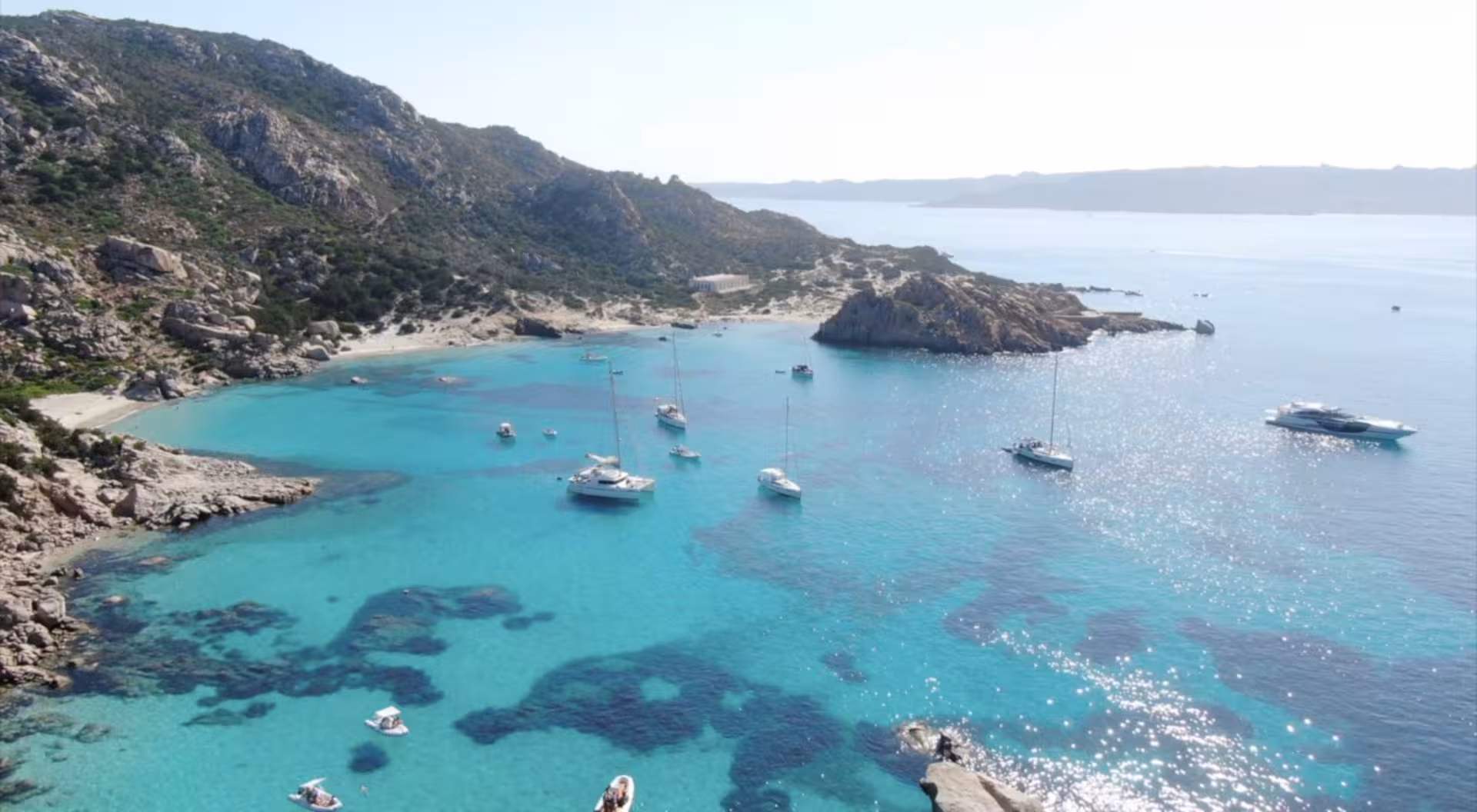 Aerial view of sailboats in the turquoise waters of La Maddalena Archipelago, perfect for a motorboat tour.