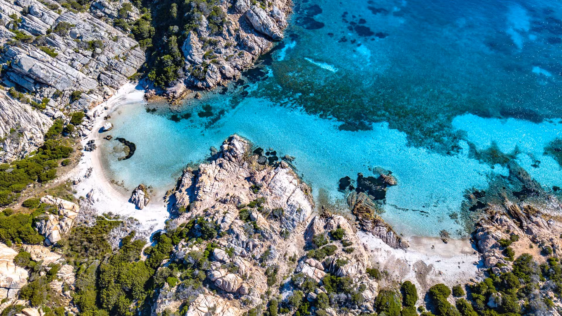 Aerial view of a secluded beach with emerald waters in the La Maddalena Archipelago, perfect for private RIB tours.